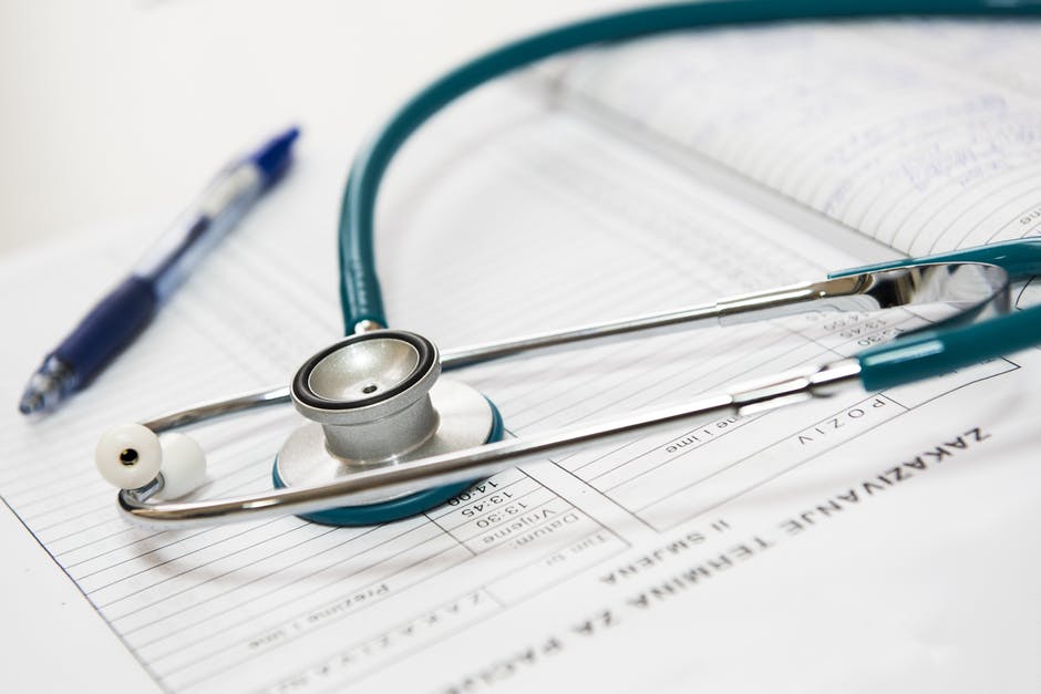 A stethoscope and pen sitting on a medical tablet.